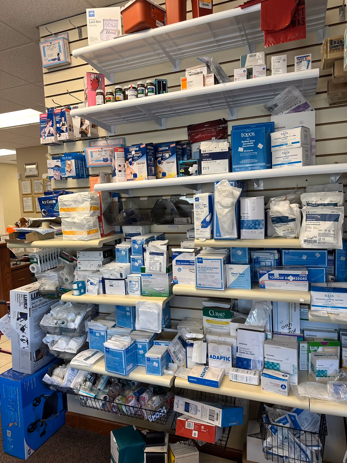 Indoor shelves filled with assorted medical supplies and boxes in a clinic supply area.
