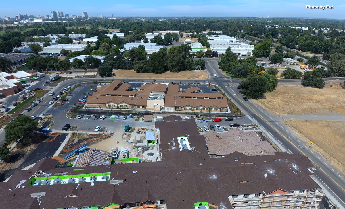 Aerial view of a large multi-building senior living campus with brown roofs and surrounding roads