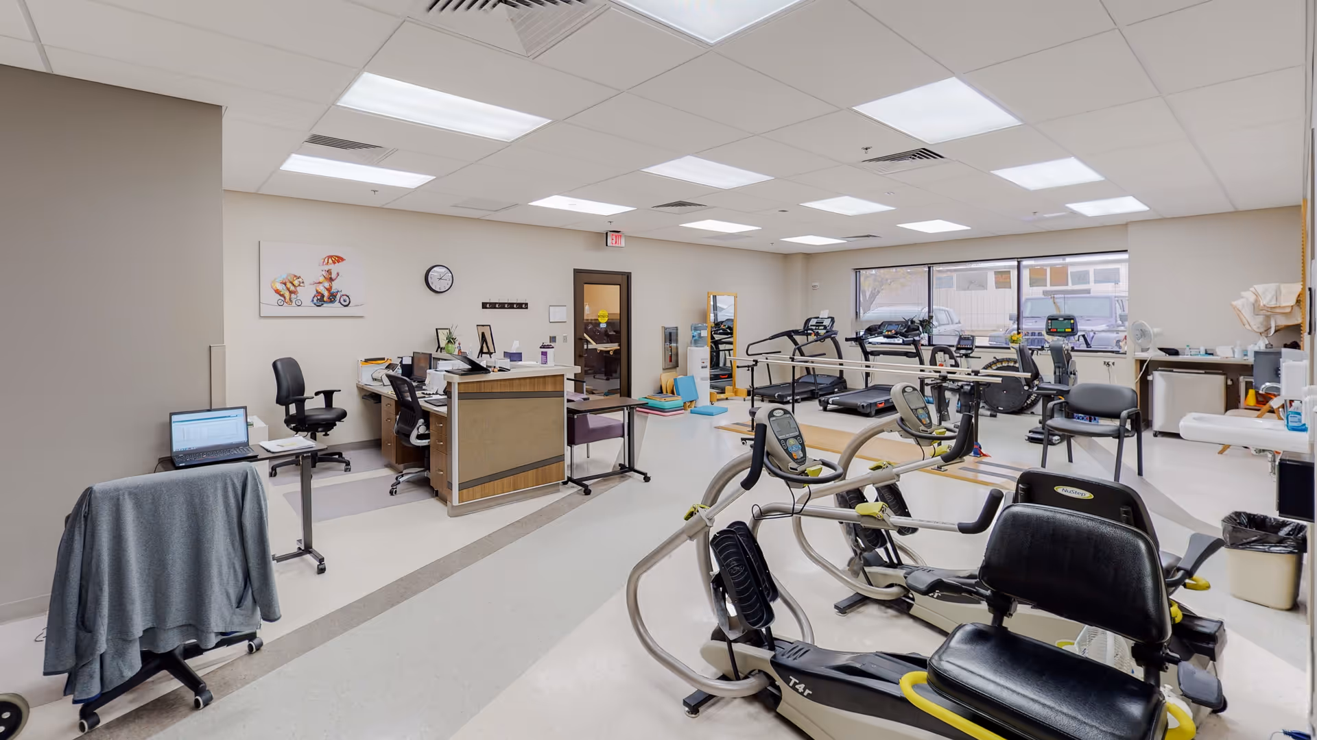 Bright Minneola District Hospital rehab gym with treadmills, bikes, and desks.