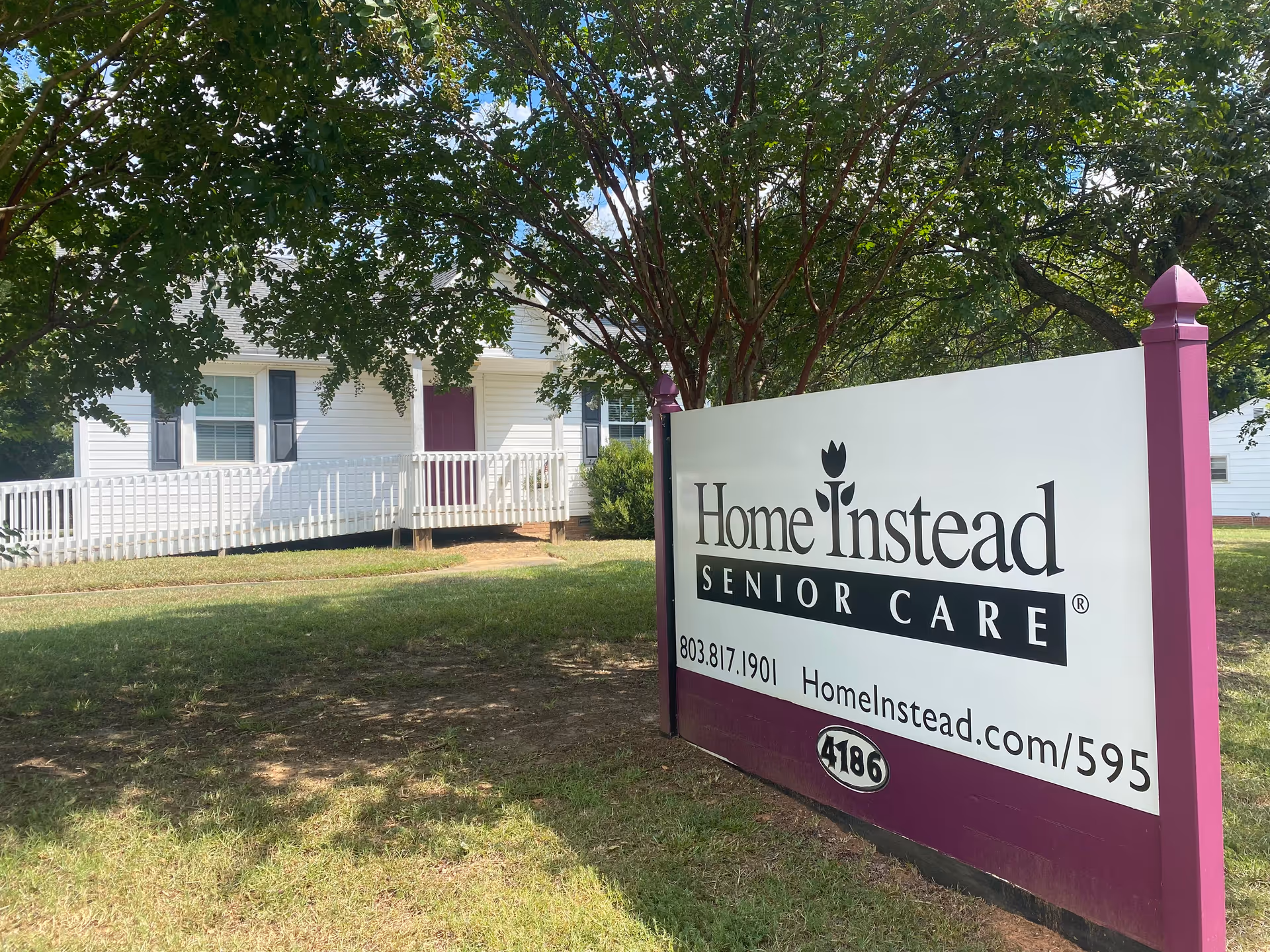 Front view of a senior care facility with a Home Instead sign near a white porch.