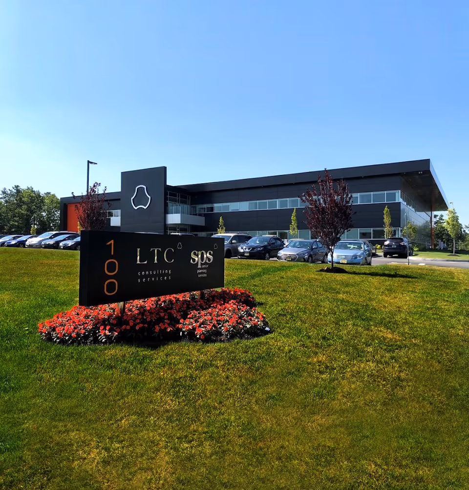 Modern two-story building with a large sign and a row of parked cars in front.