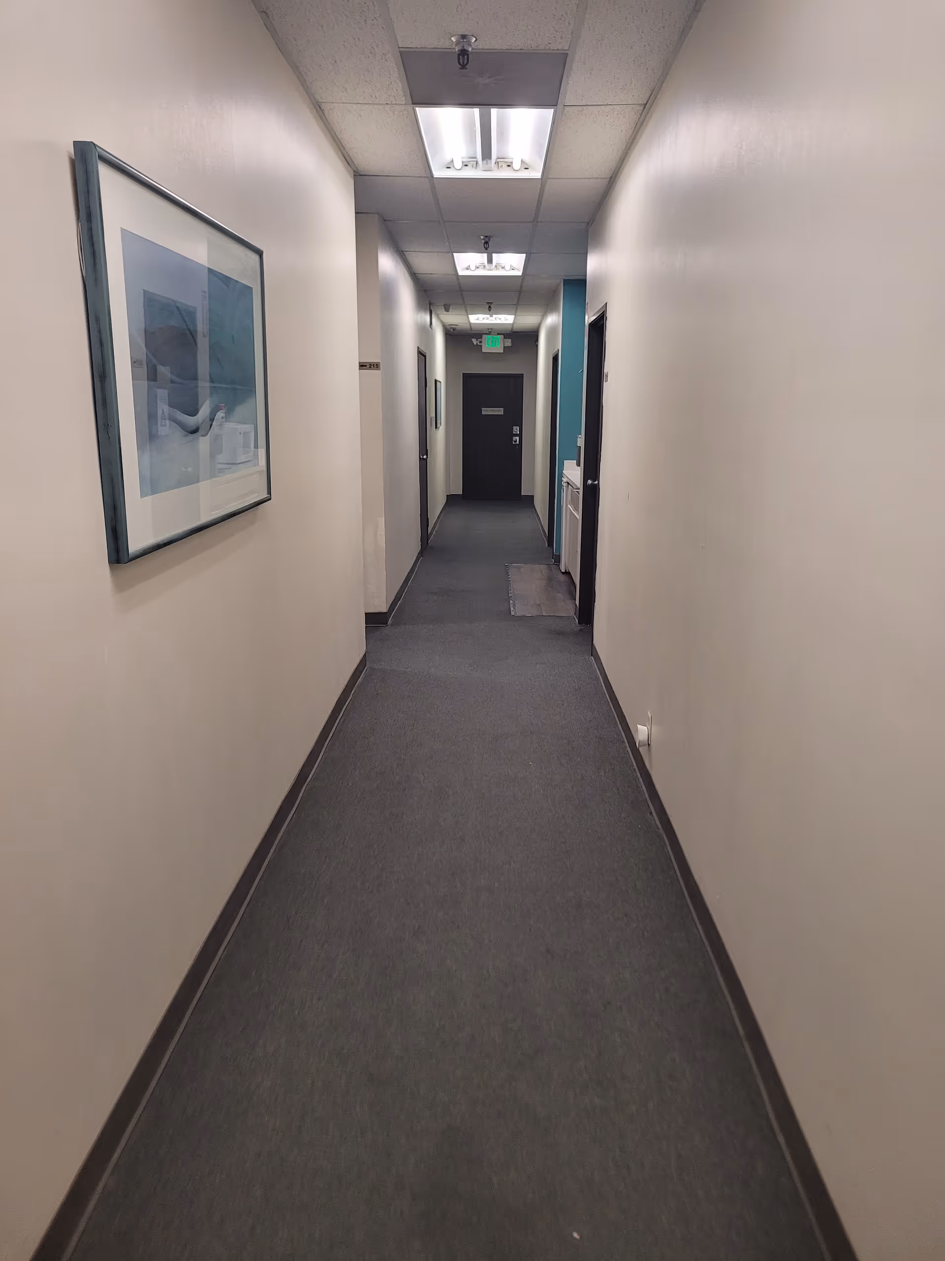 A long, well-lit hallway in a senior living facility with framed art.