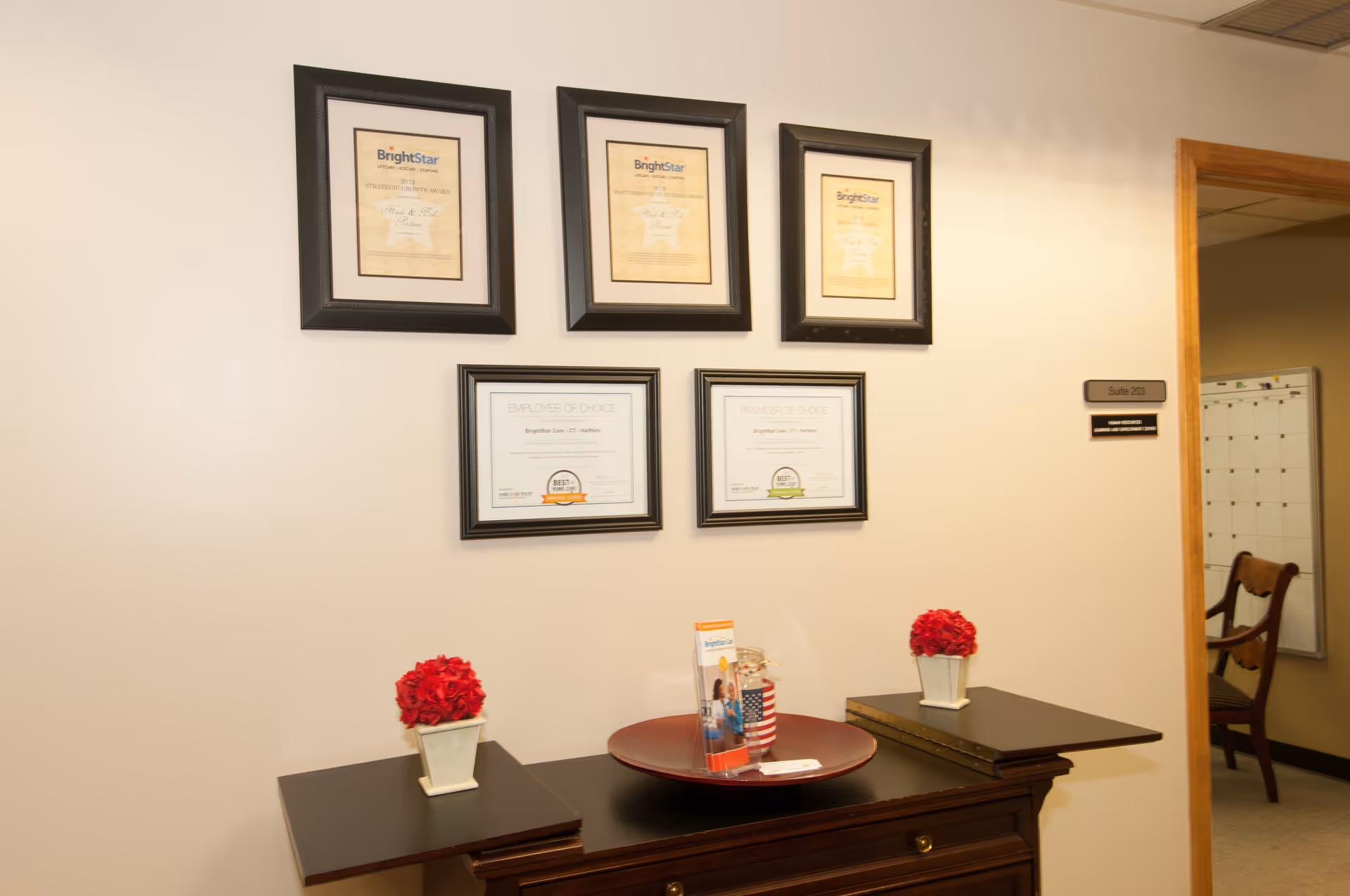 BrightStar Care reception area with framed certificates and red flowers.