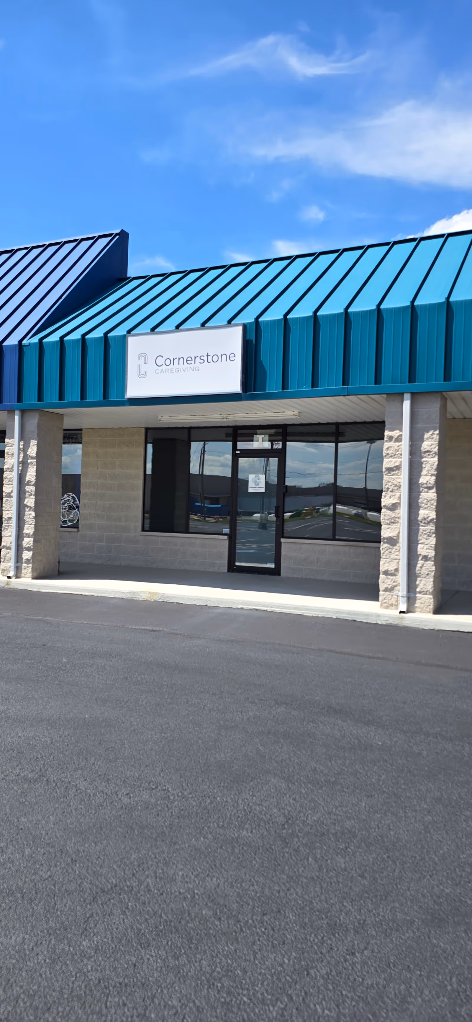Front view of Cornerstone Caregiving building with teal metal roof and glass entrance.
