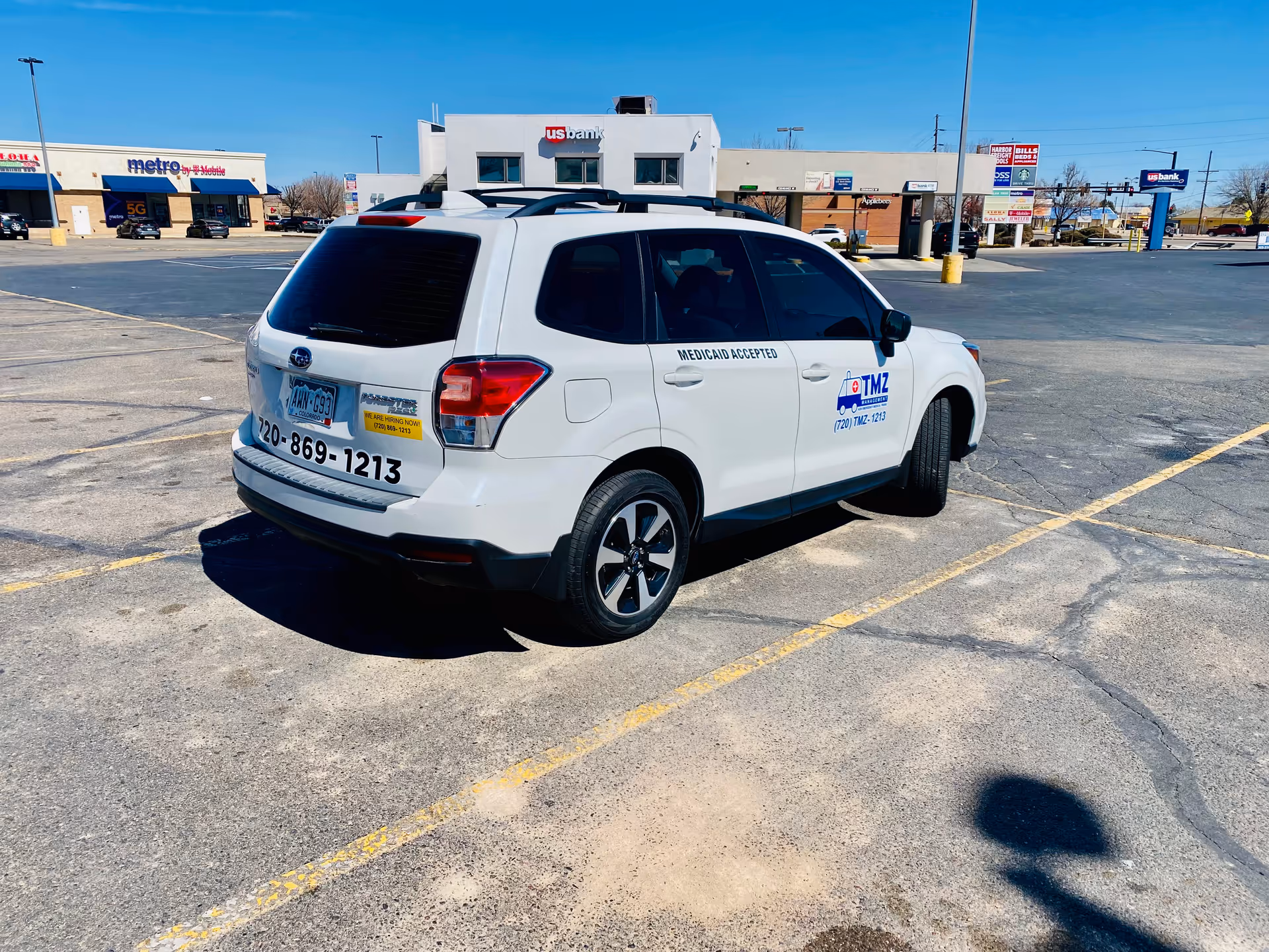 White TMZ Medical Transportation SUV parked in a large empty parking lot near storefronts.