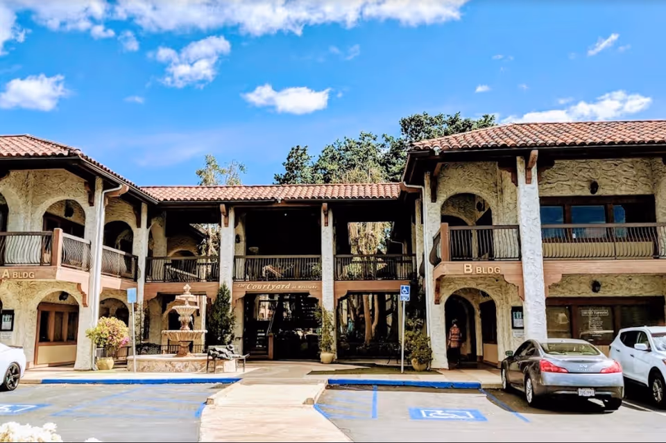 Exterior view of 1Heart Caregiver Services building with a courtyard fountain.