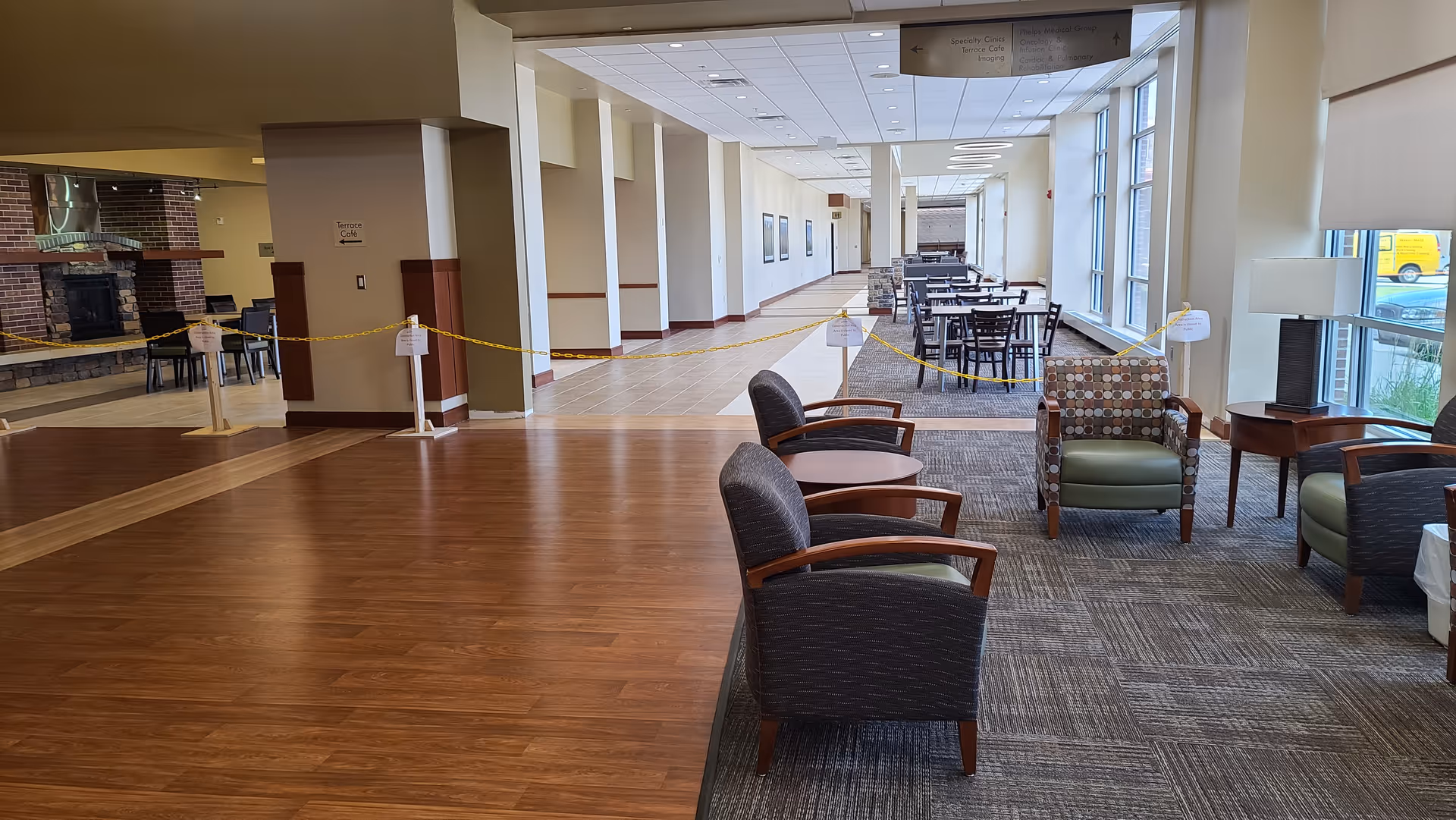 Spacious senior living lobby with chairs, tables, carpet, and a taped-off area to the left.