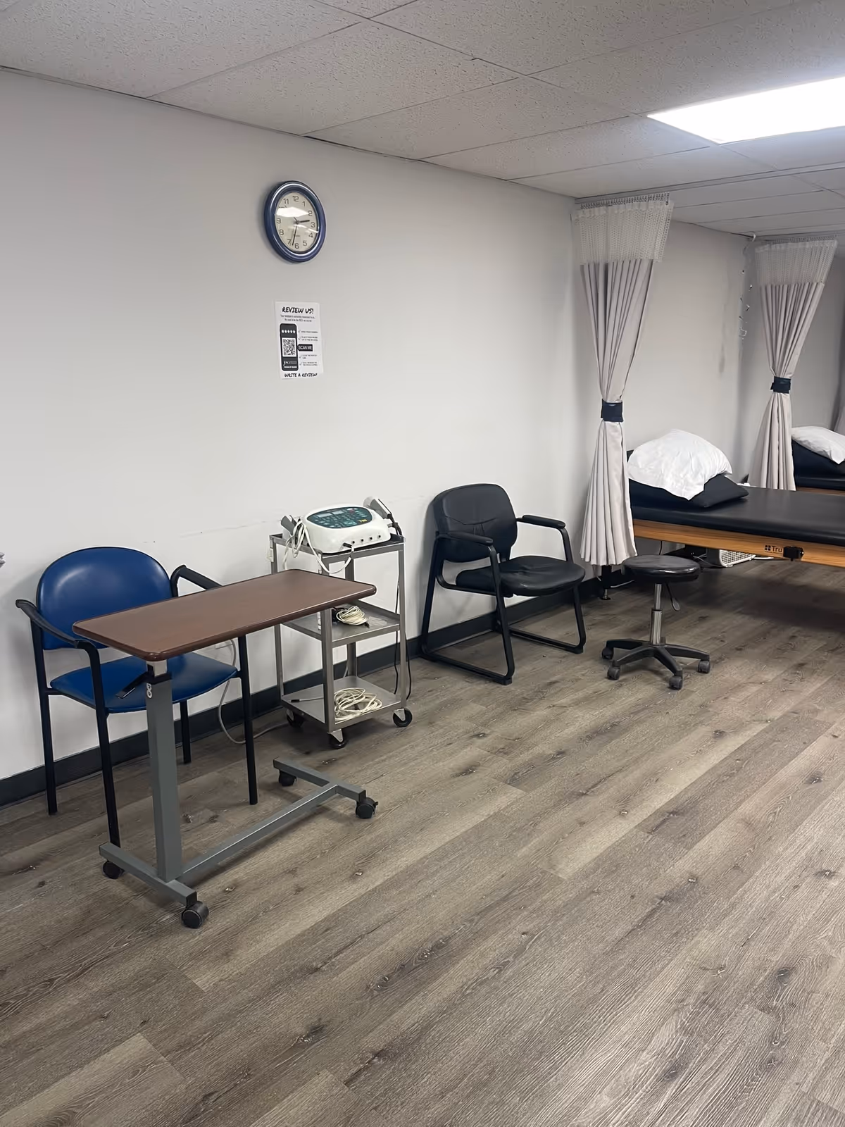 Interior physical therapy room with curtained beds, chairs, and medical equipment.
