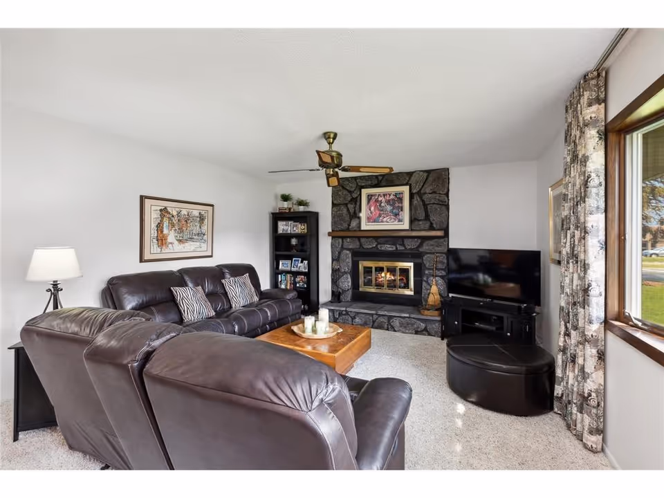 Cozy living room with stone fireplace, leather seating, and a TV.