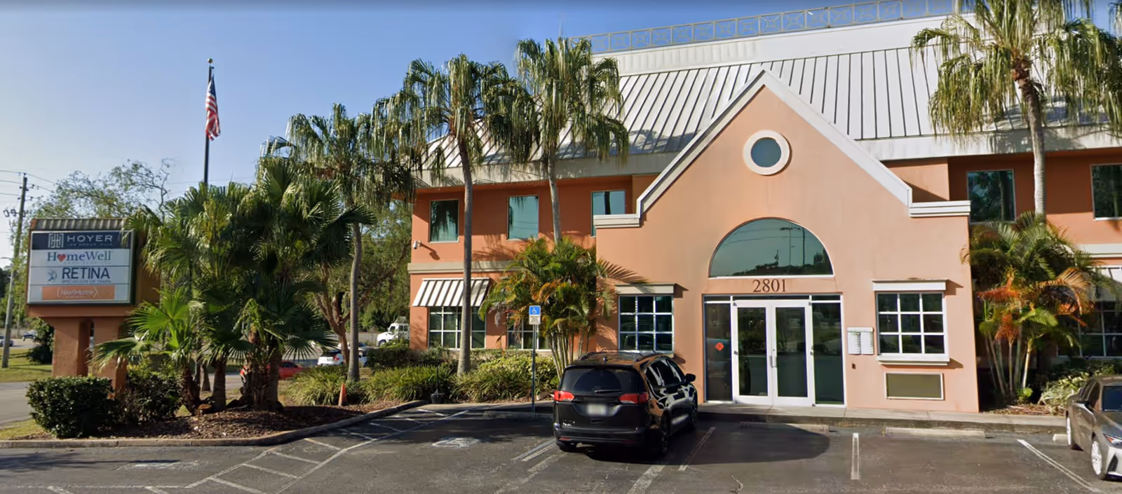 Exterior view of a peach-colored HomeWell Care Services building with palm trees and a parking lot.