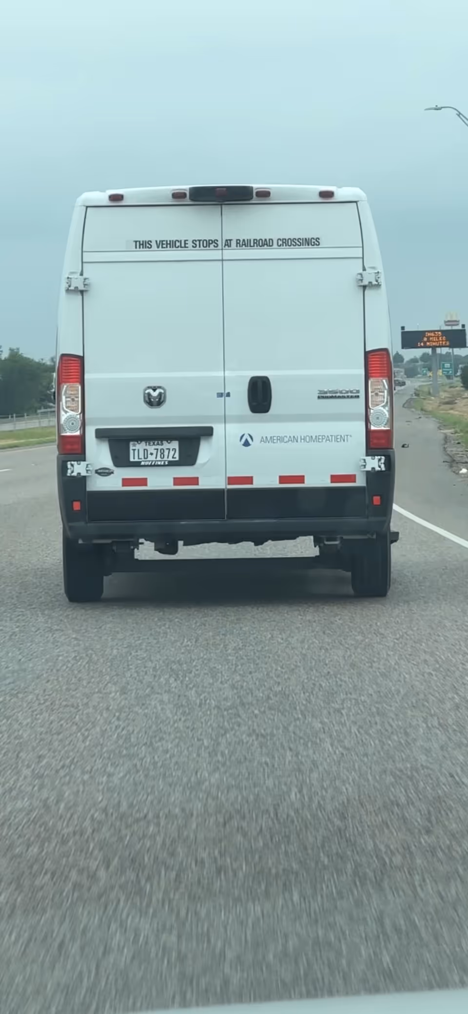 Rear view of a white American HomePatient transport van on a highway.