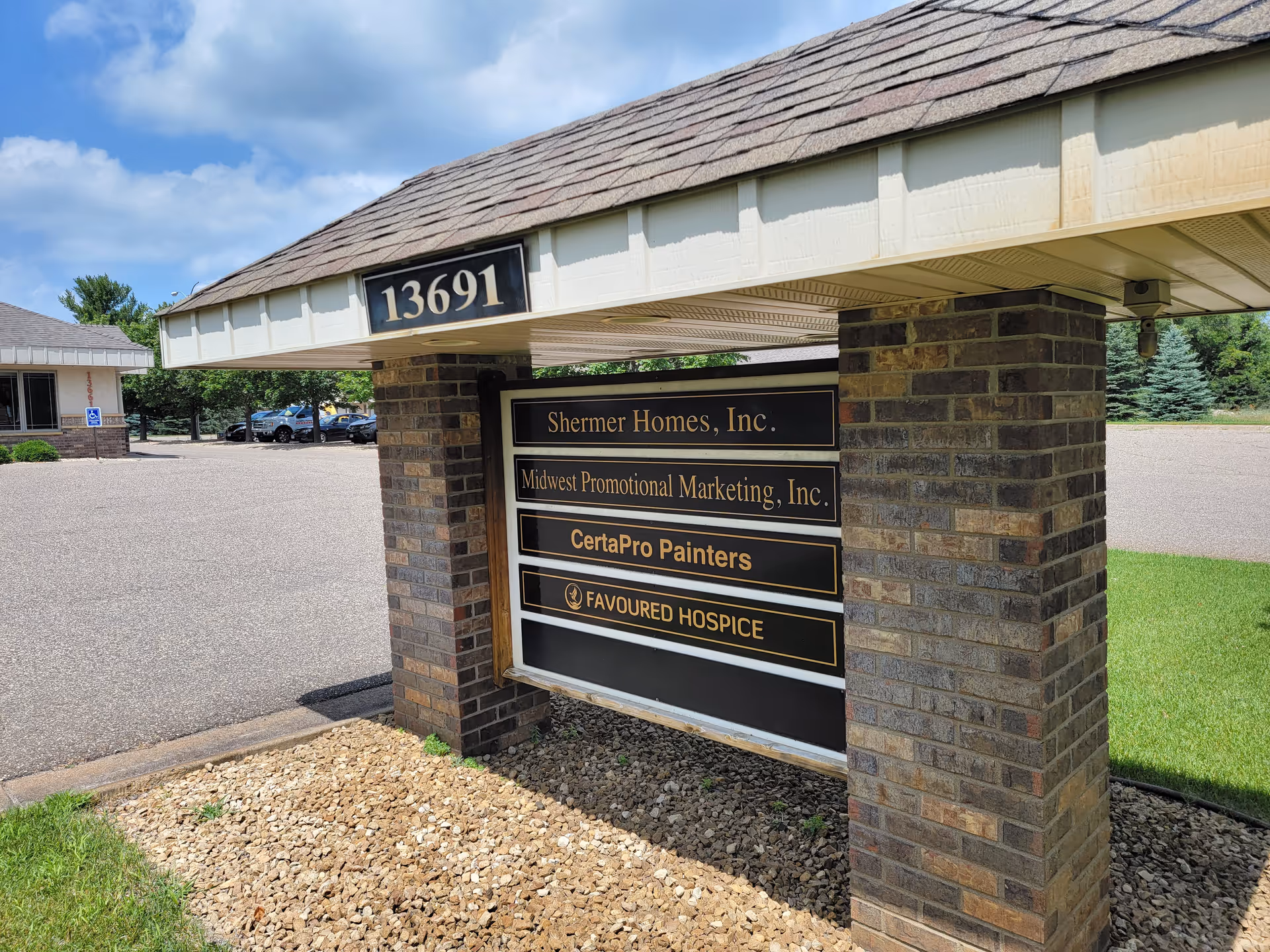 Exterior brick building with a signboard listing Favoured Hospice among other tenants.