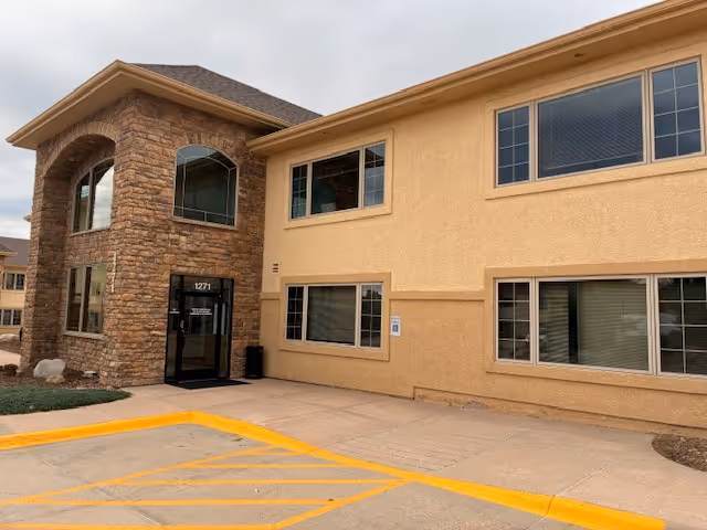 Exterior view of Comfort Keepers Home Care building with stone-front entrance.