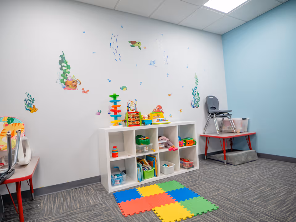 Bright children's play corner with cubbies, colorful toys, foam mat, and undersea wall decals.