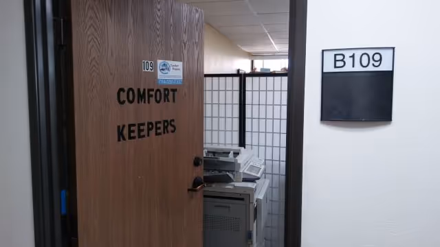 Open door shows 'Comfort Keepers' sign beside office equipment inside.