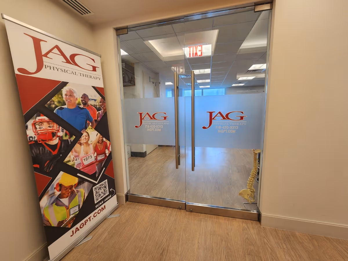 Interior hallway with glass doors branded JAG Physical Therapy, and a skeleton model beside the entry.