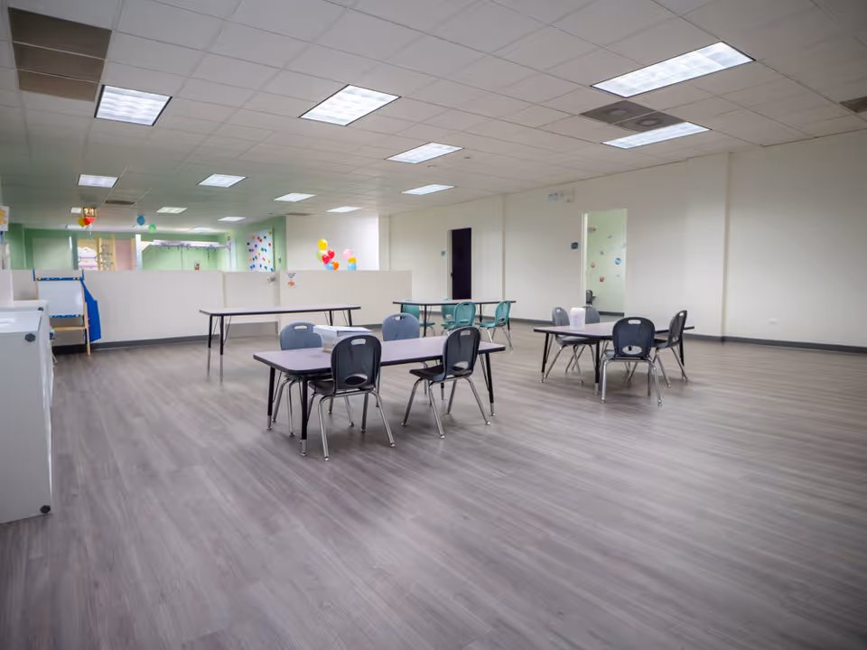 Large empty interior room with tables, chairs, and balloons in a senior facility.