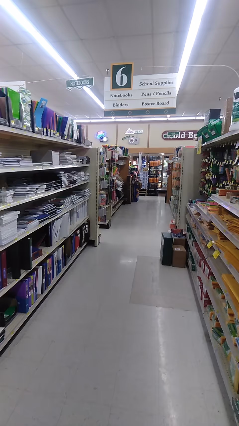 Inside Discount Drug Mart, a long aisle with shelves of notebooks and school supplies.