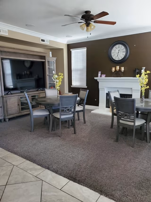 Living room and dining area with round tables, chairs, TV, and fireplace.