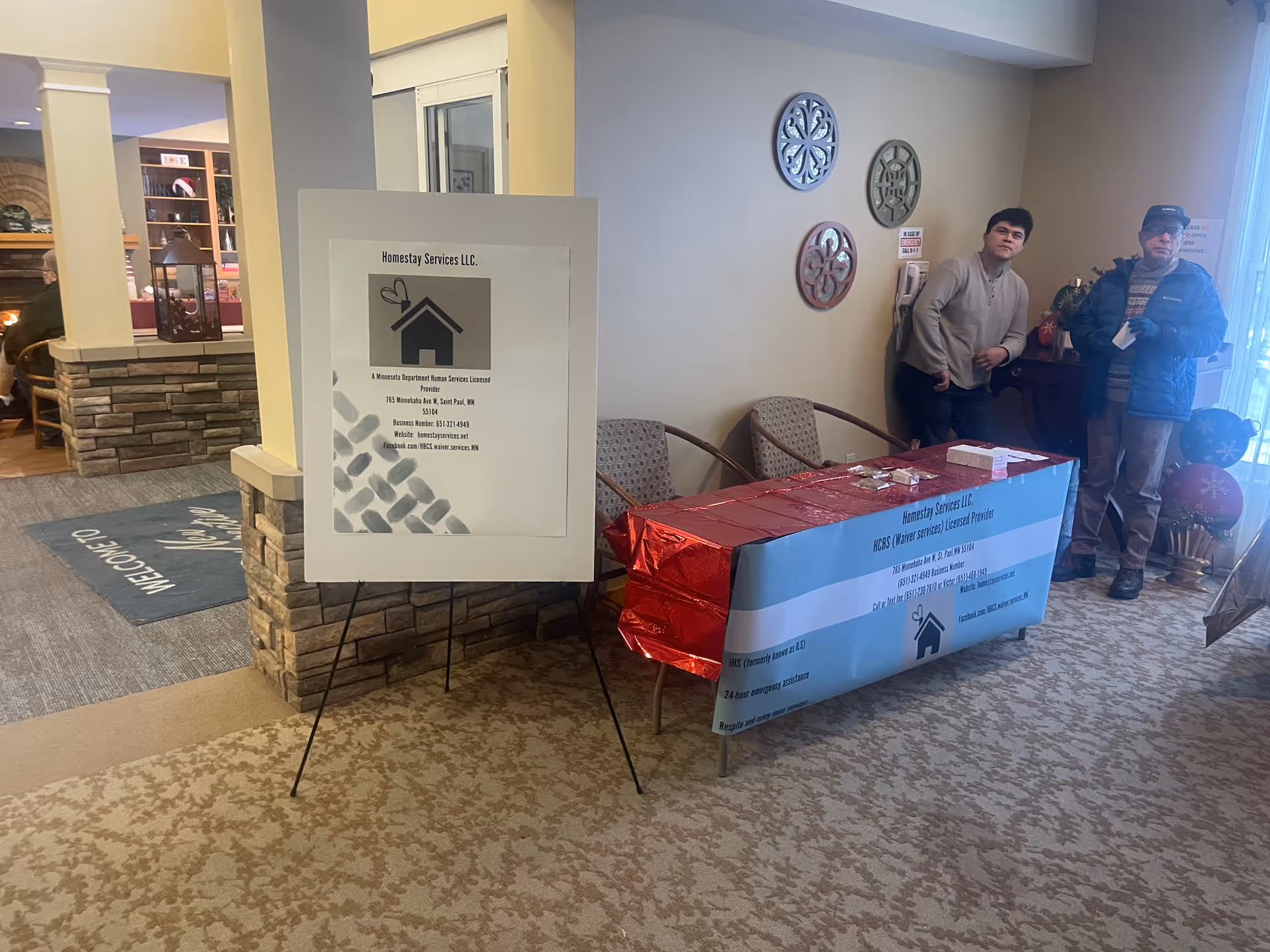 Lobby reception area for Homestay Services LLC with a banner and two men.