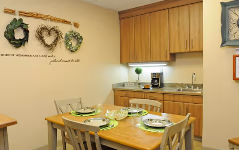 Dining table set for a meal in a small communal kitchen and dining area.