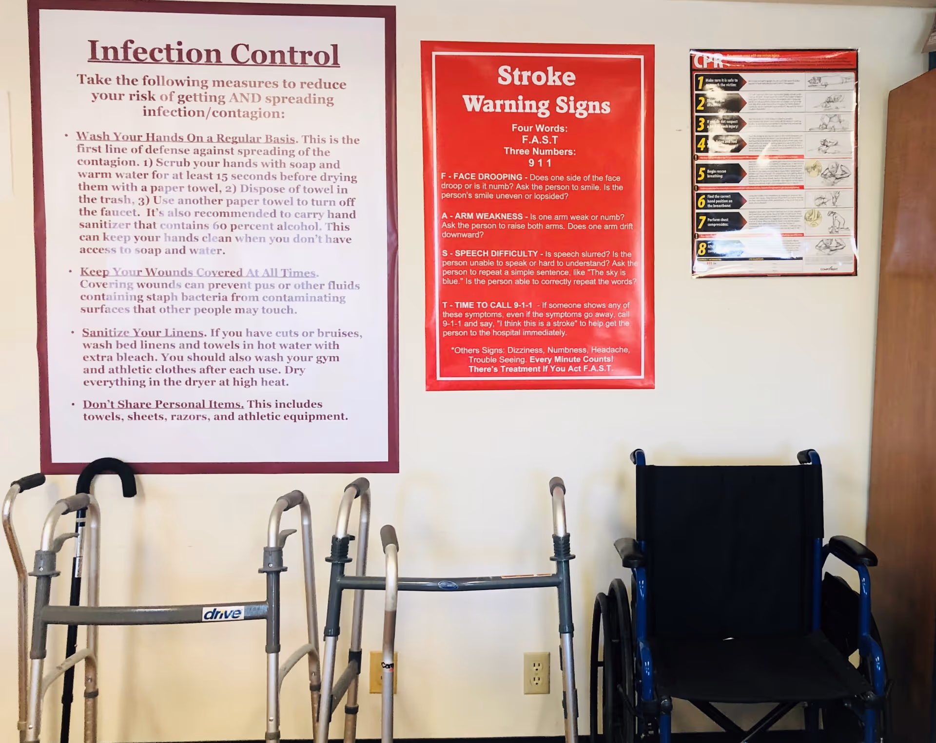 Interior wall with infection-control posters, a wheelchair, and walkers.