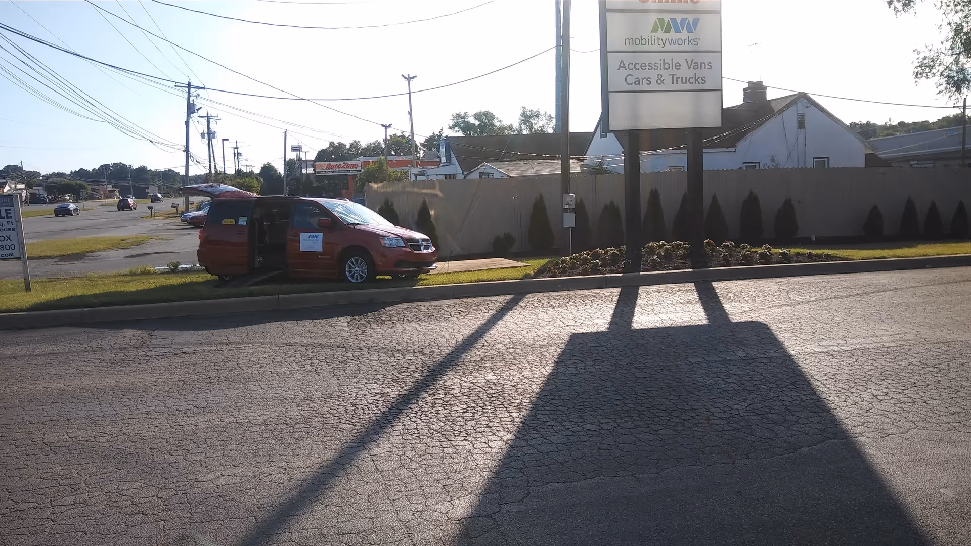 Red accessible van parked near MobilityWorks exterior sign along a road