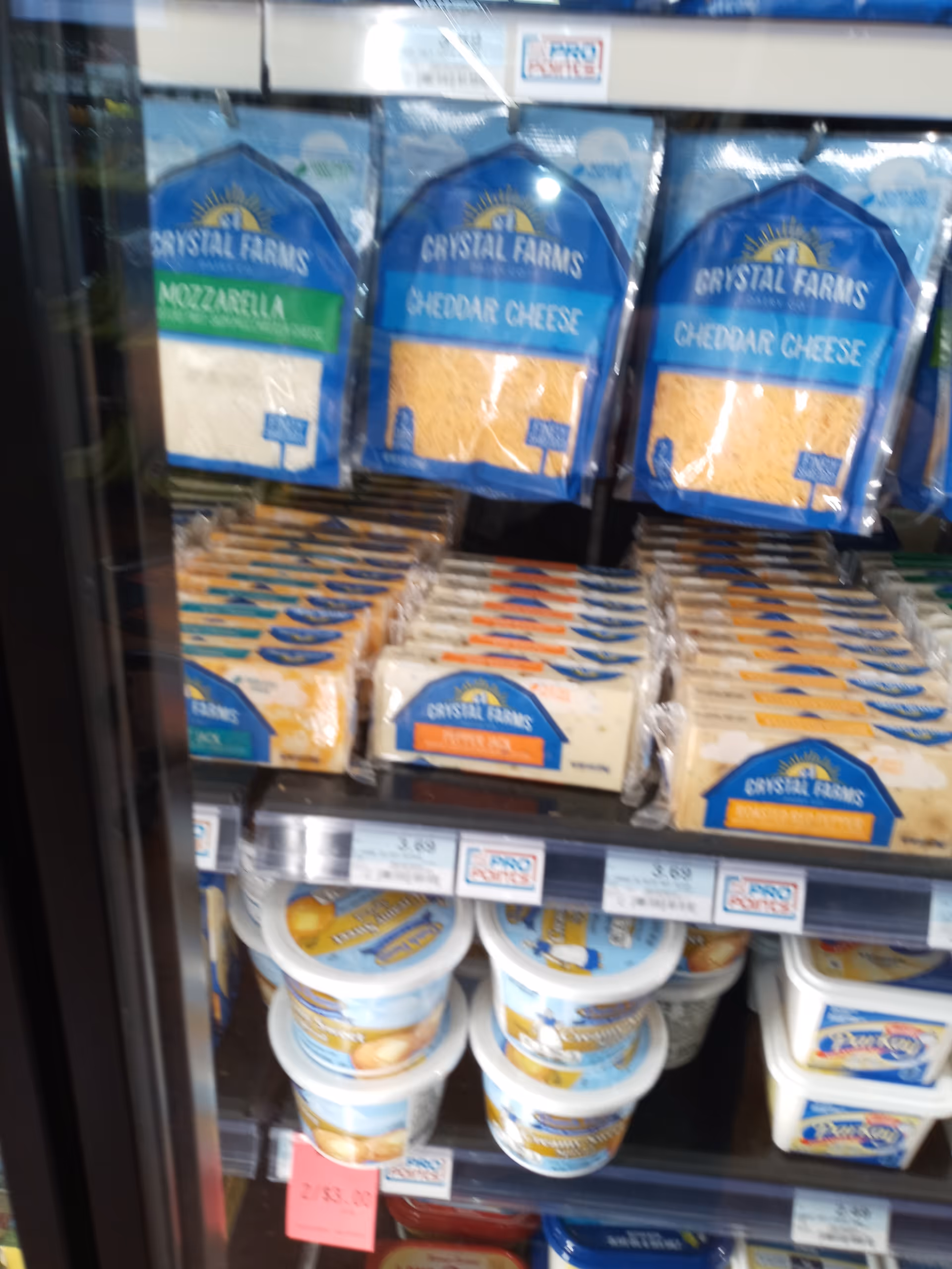 Refrigerated display of Crystal Farms cheese and dairy products on a shelf.