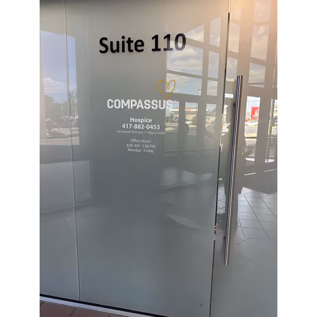 Glass entrance door showing Suite 110 and COMPASSUS Hospice signage in a lobby.
