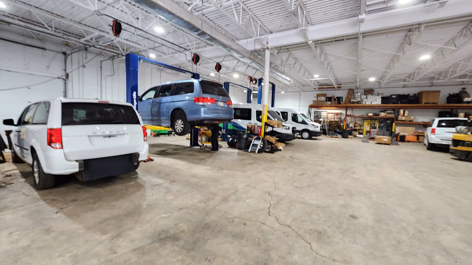 Inside MobilityWorks shop, cars on lifts in a large service bay with tools.