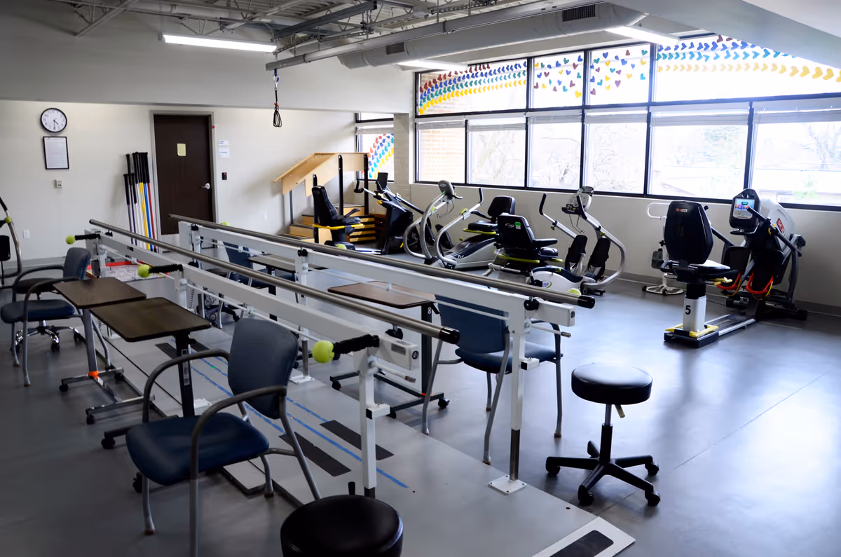Rehabilitation gym in a senior facility with treadmills, stationary bikes, and therapy equipment.