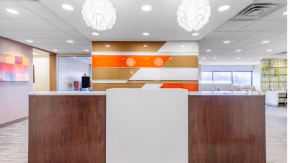 Modern senior living lobby with a white reception desk and colorful wall art.