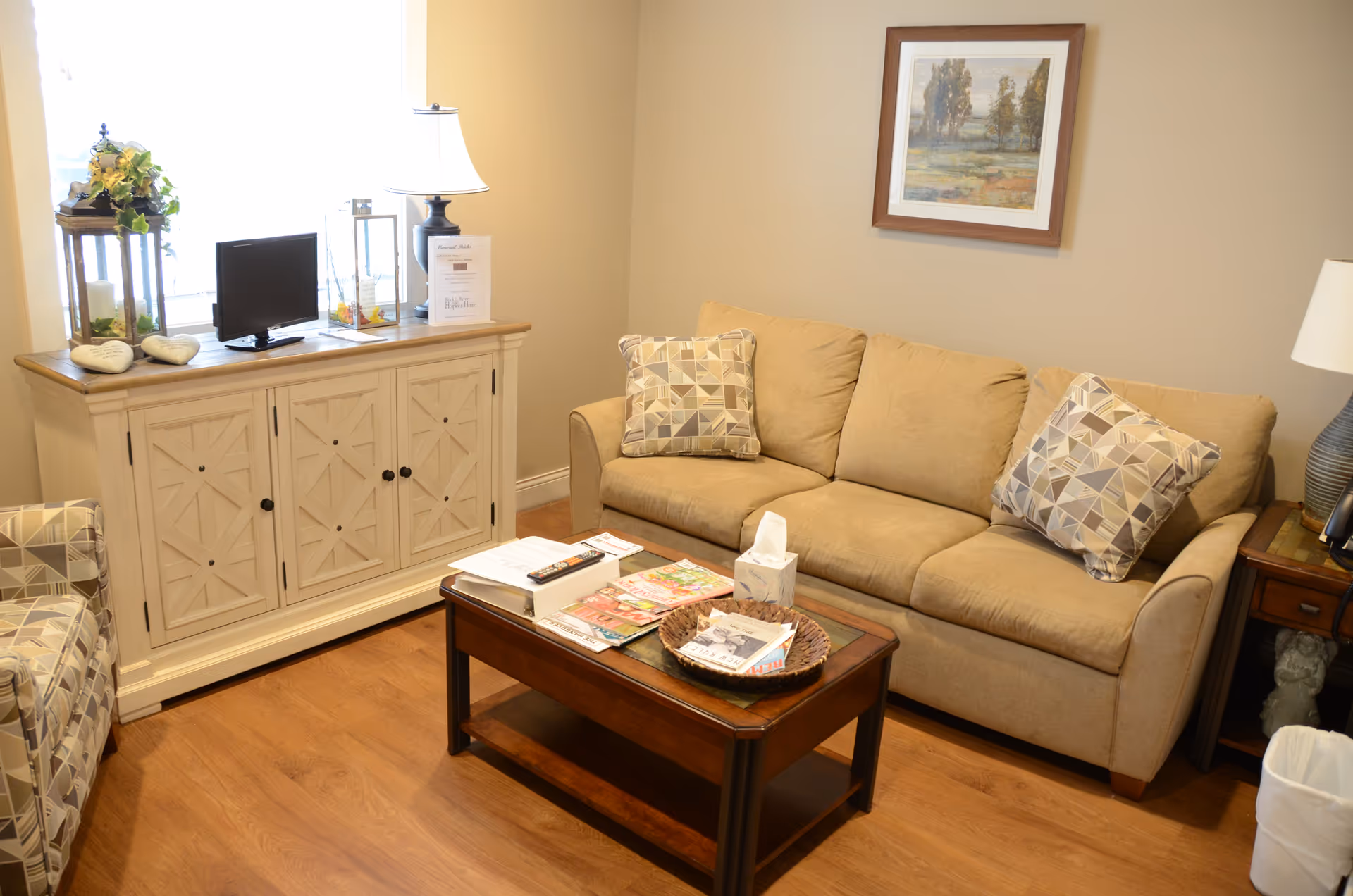 A cozy beige living room in a senior facility with sofa, coffee table, and decor.