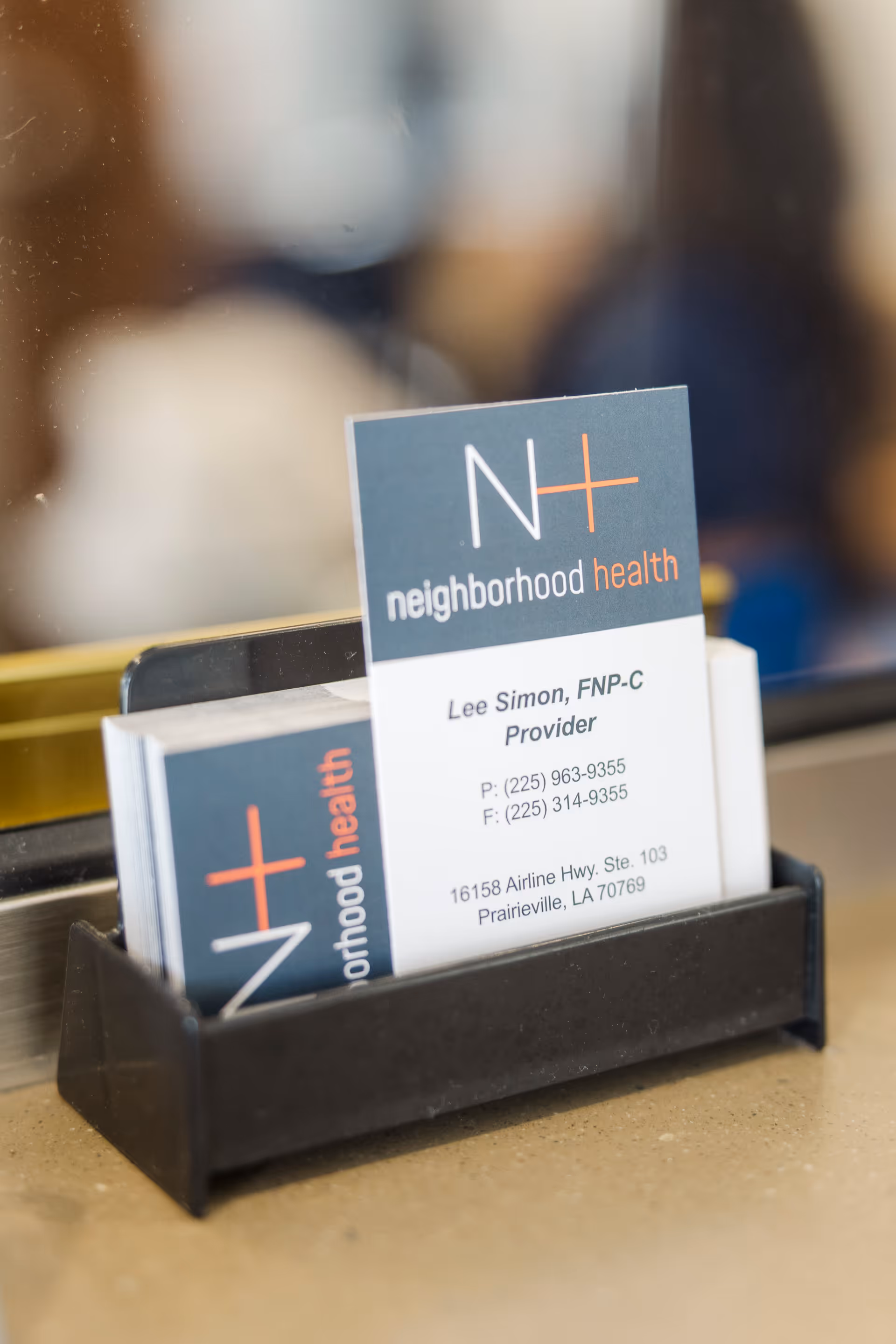 Black brochure holder on a beige counter displaying Neighborhood Health cards.