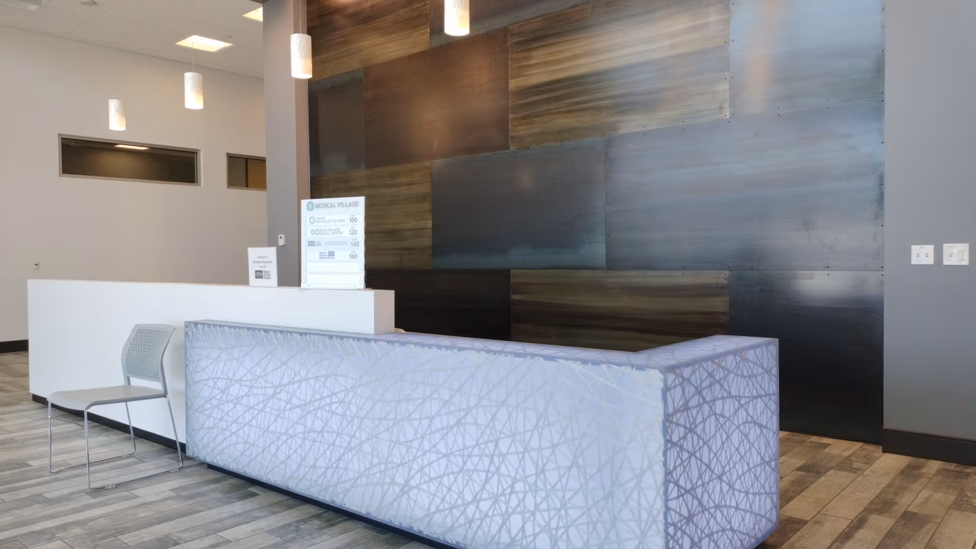 Modern lobby reception desk with a patterned light-blue front and wood-panel wall behind.