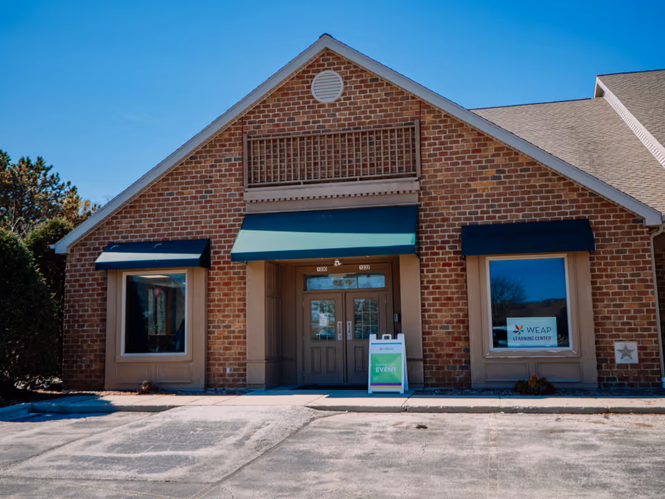 Front view of a brick building entrance with WEAP Learning Center sign.
