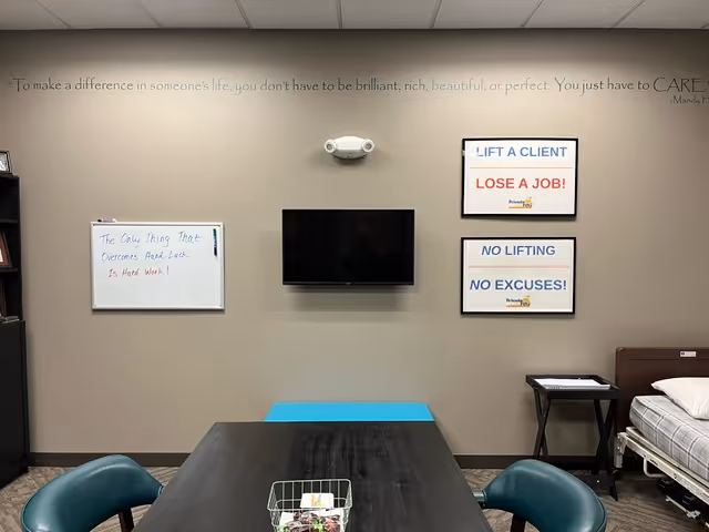 Interior senior care room with table, chairs, TV, whiteboards, and posters.
