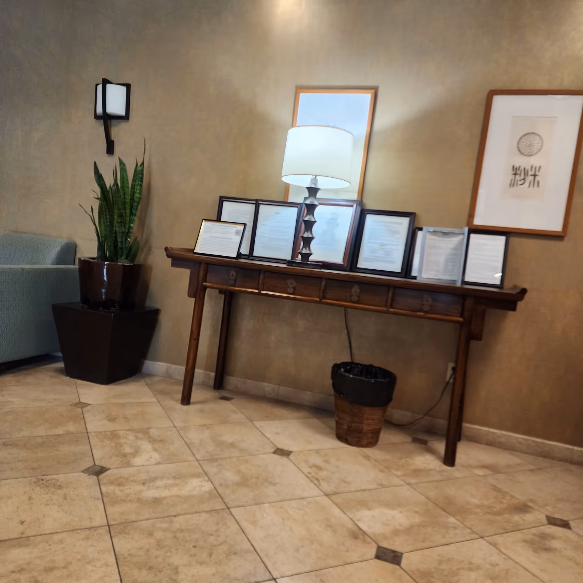 Lobby at Specialty Surgical Center of Encino with a console, frames, lamp, plant, and tile floor.
