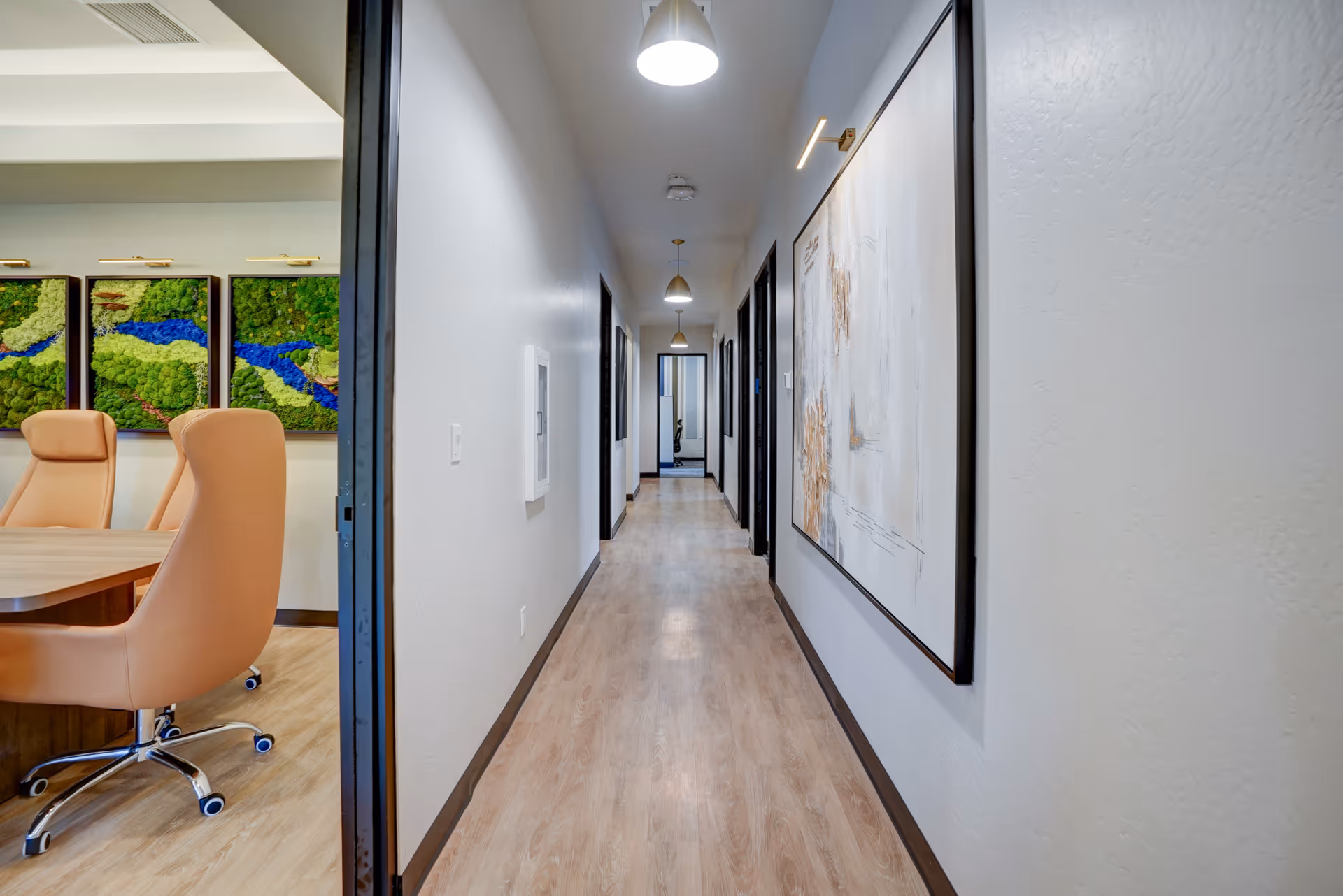 Bright corridor inside a senior living facility, with wall art and a conference room.