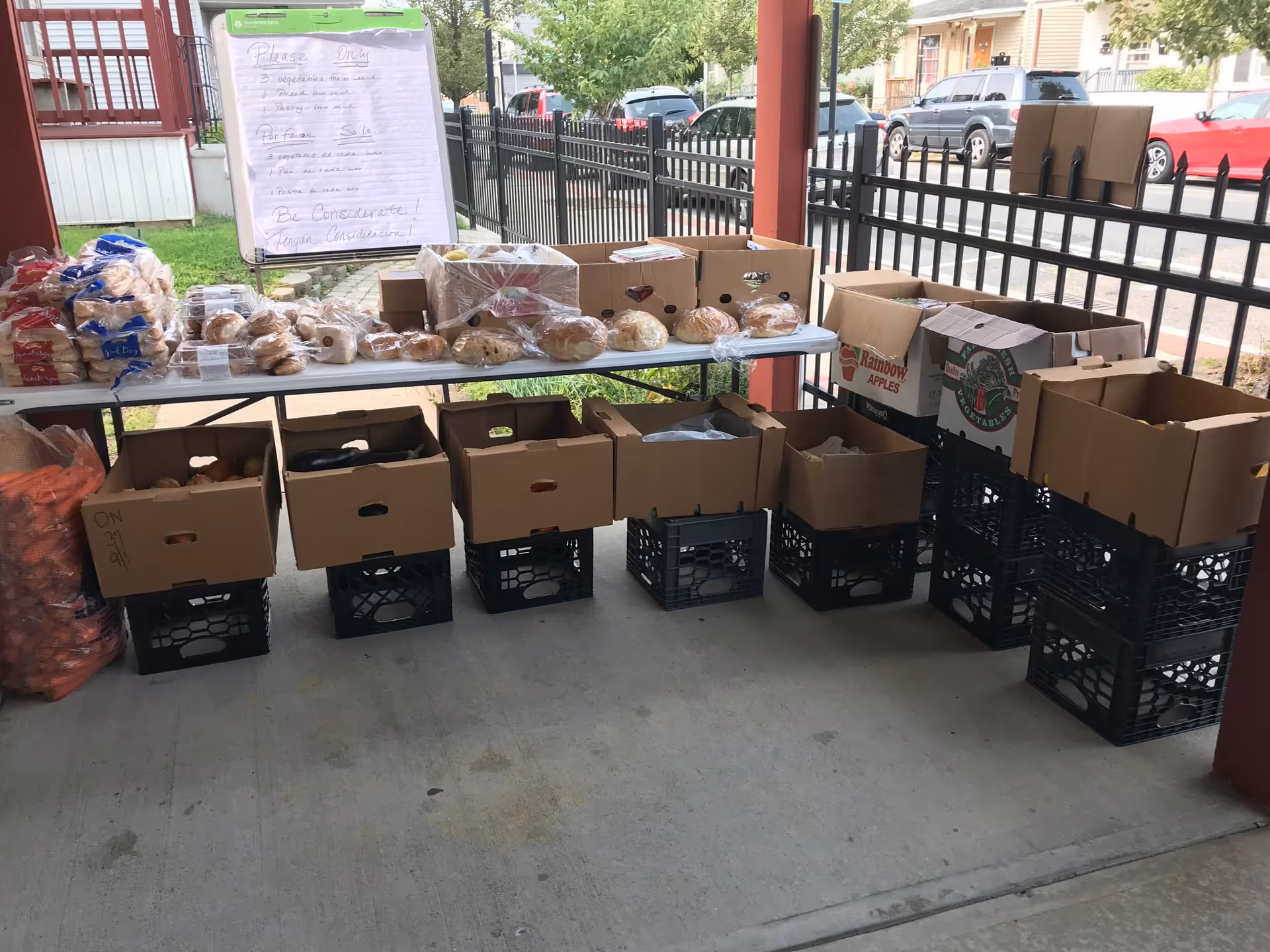 Outdoor covered area with tables and boxes of bread for distribution