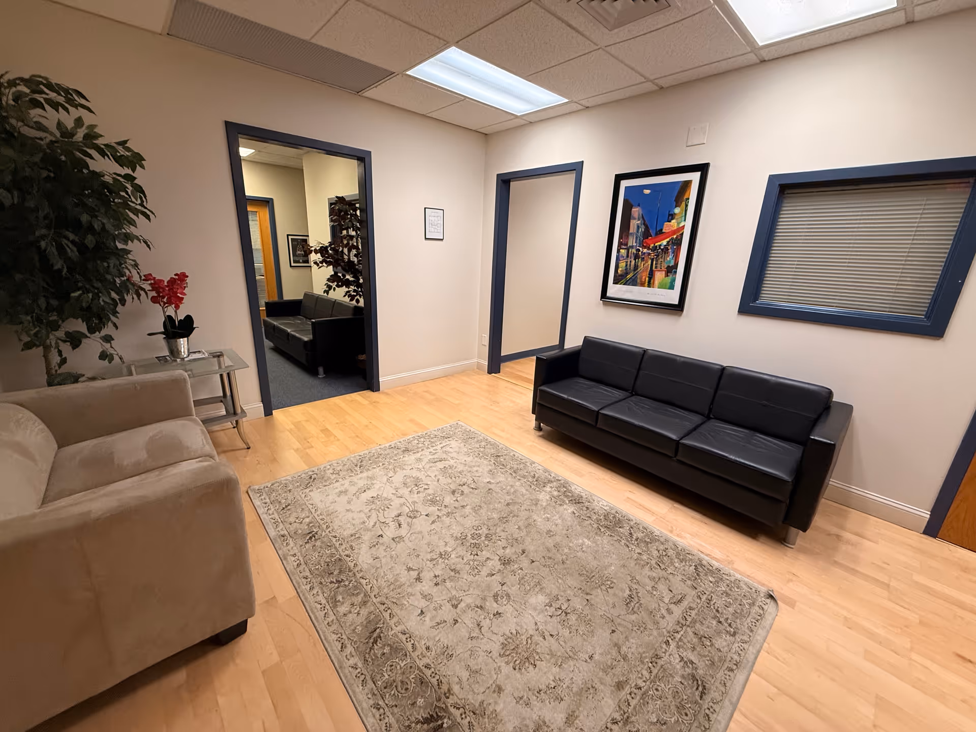A modern senior living lobby with beige and black seating, rug, and framed artwork.
