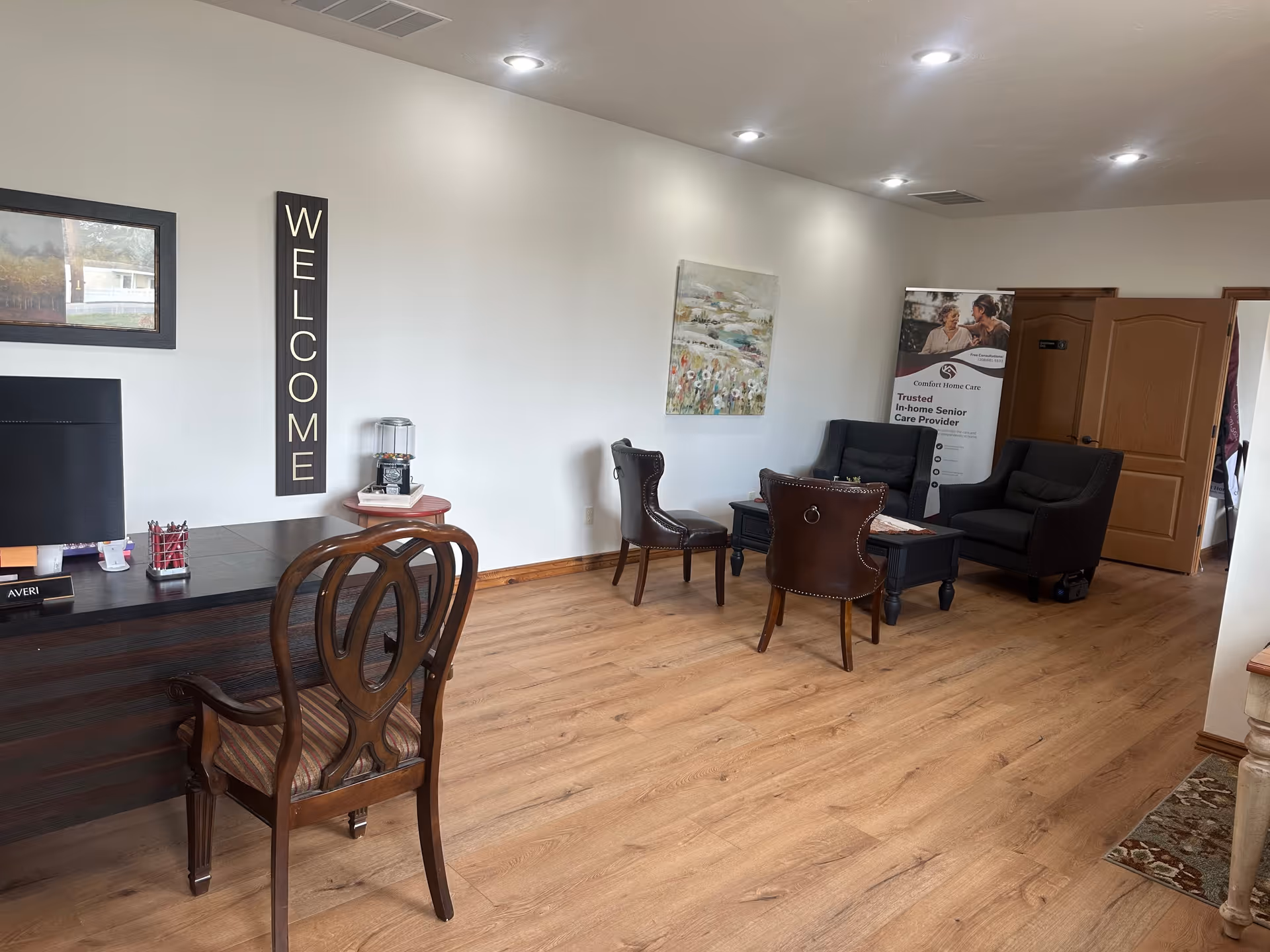 Reception lounge with wooden floors, chairs, a desk, welcome sign, and a promotional banner.