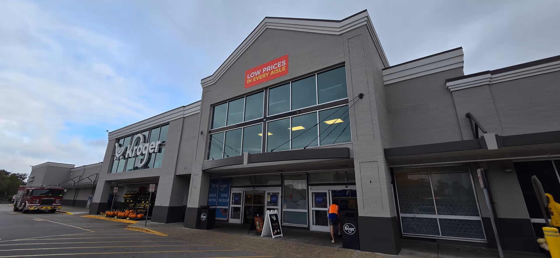Exterior view of a Kroger Pharmacy storefront with large glass entrance and pumpkins.