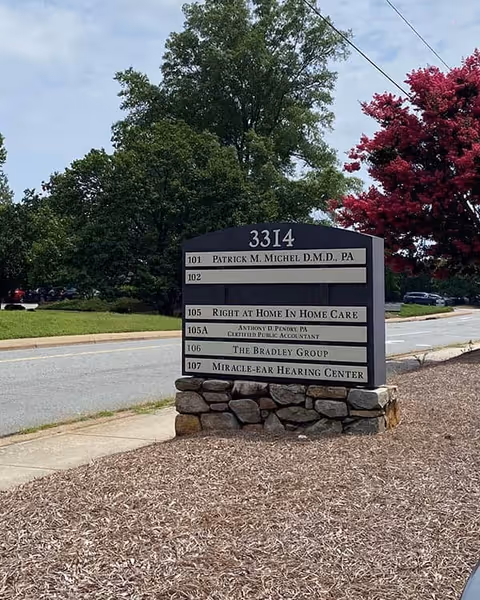 A roadside sign on a stone base lists tenants including Right at Home In Home Care.