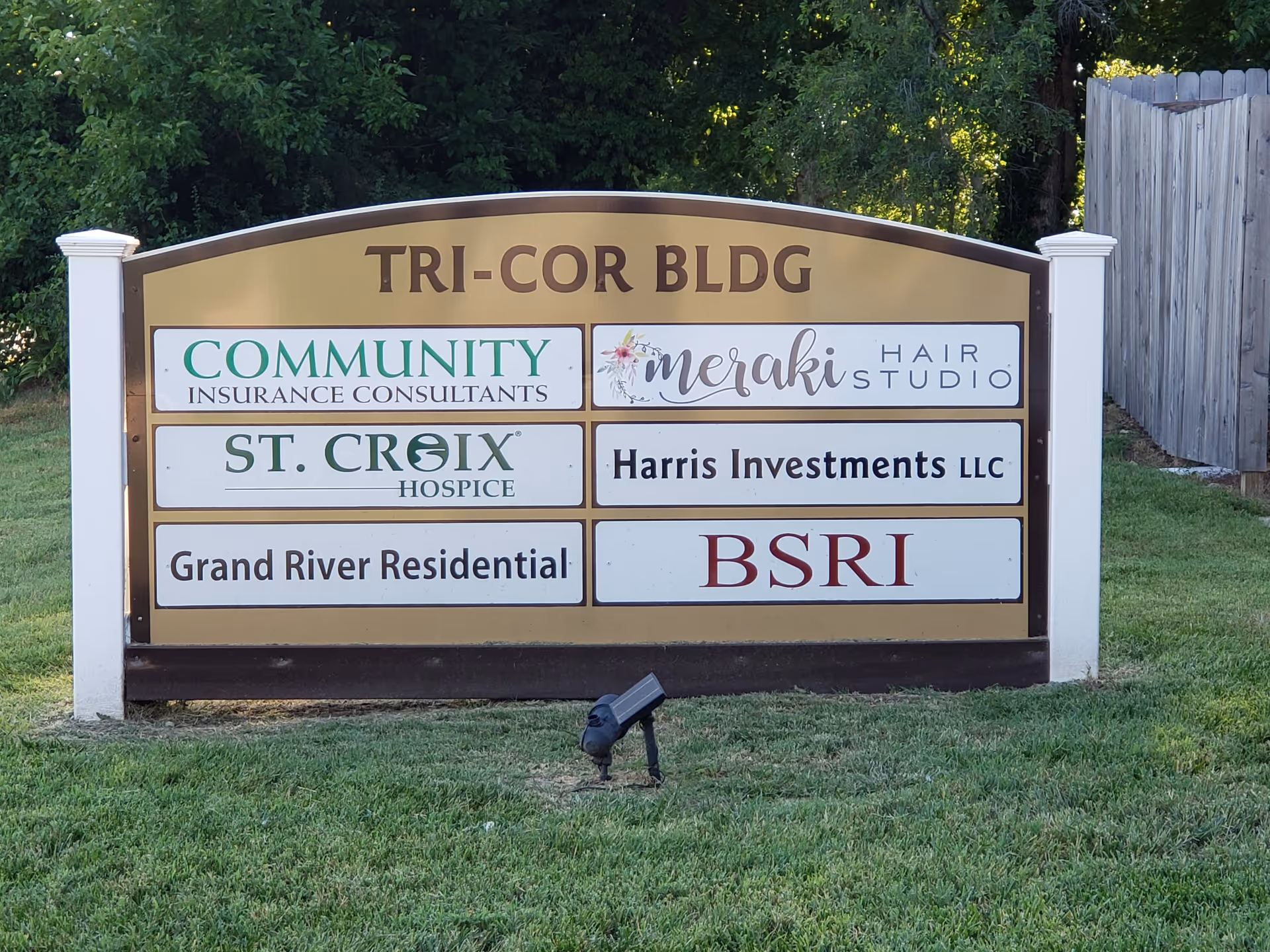 Outdoor signboard listing multiple businesses, including St. Croix Hospice, displayed on a grassy lot.