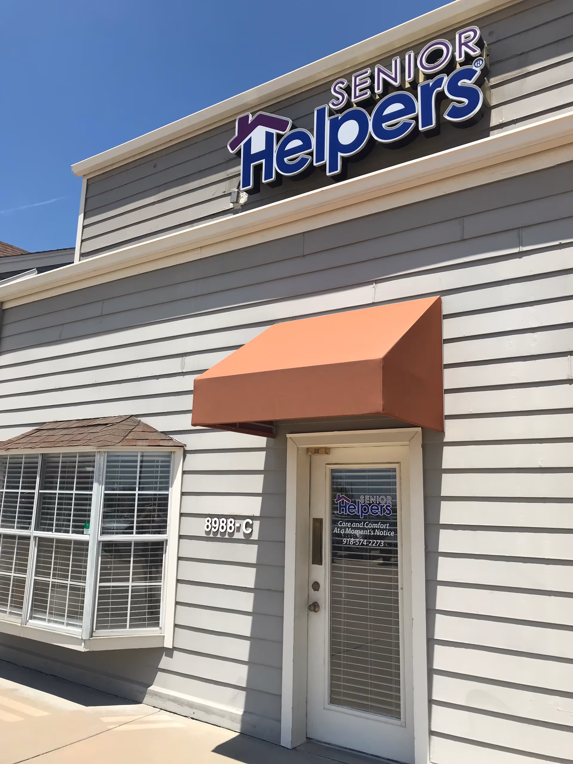 Exterior view of a Senior Helpers facility with signage and orange awning.