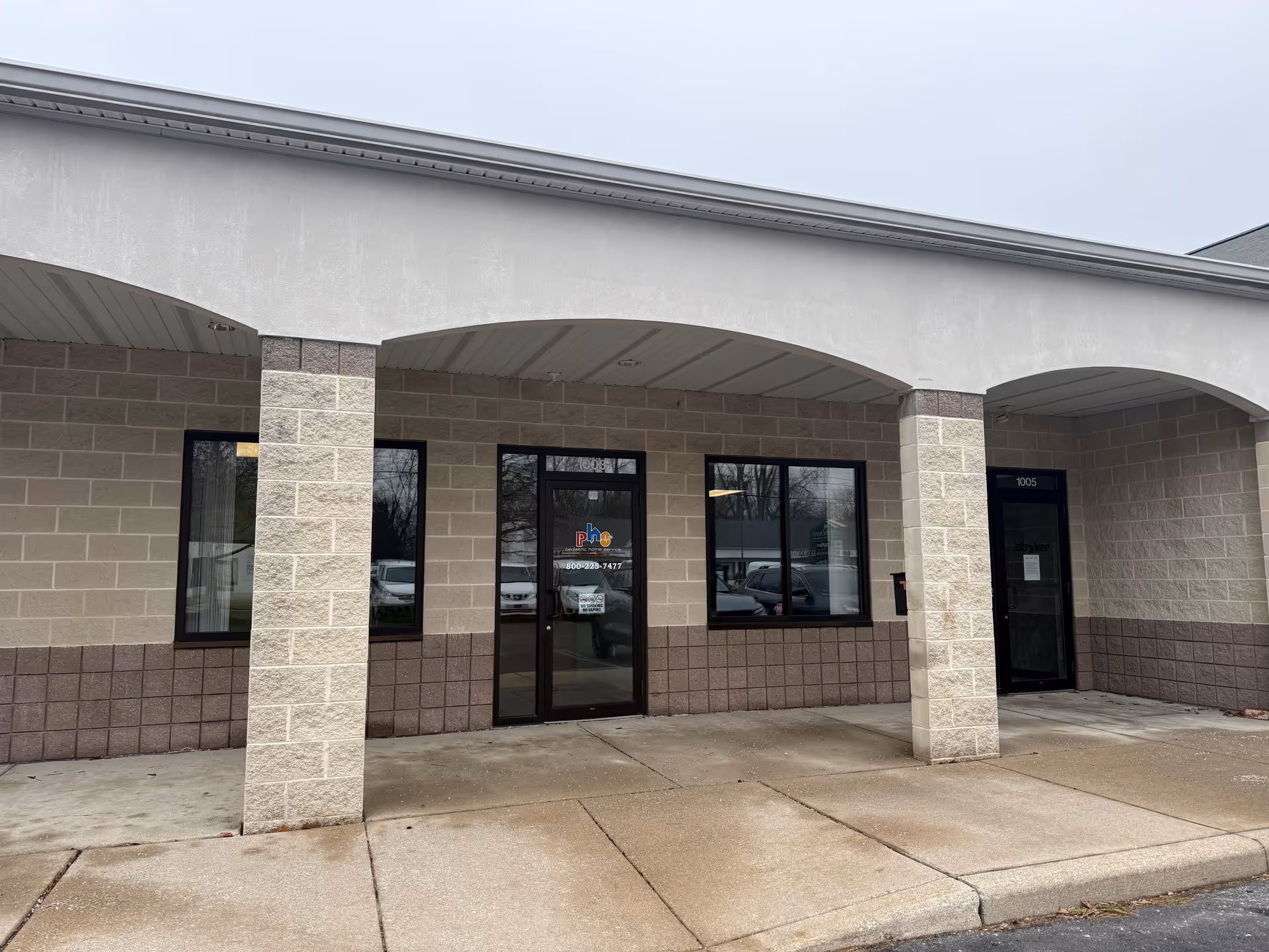 Exterior view of a beige brick building entrance with columns and glass doors
