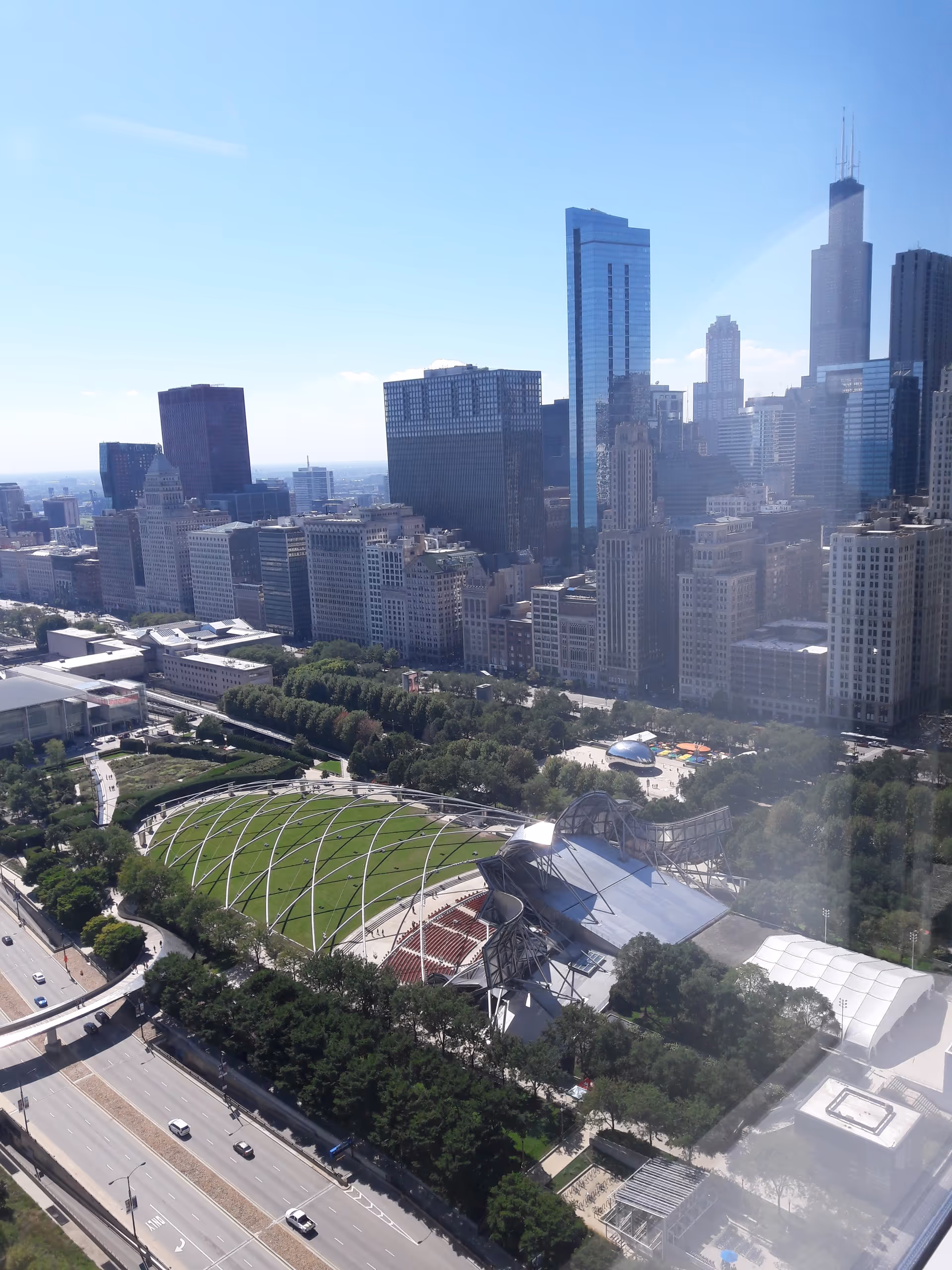 A city skyline viewed from above with Millennium Park's green lawns and glass structures.