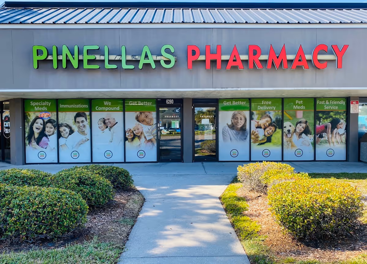 Front view of PINELLAS PHARMACY storefront with large green and red signage.