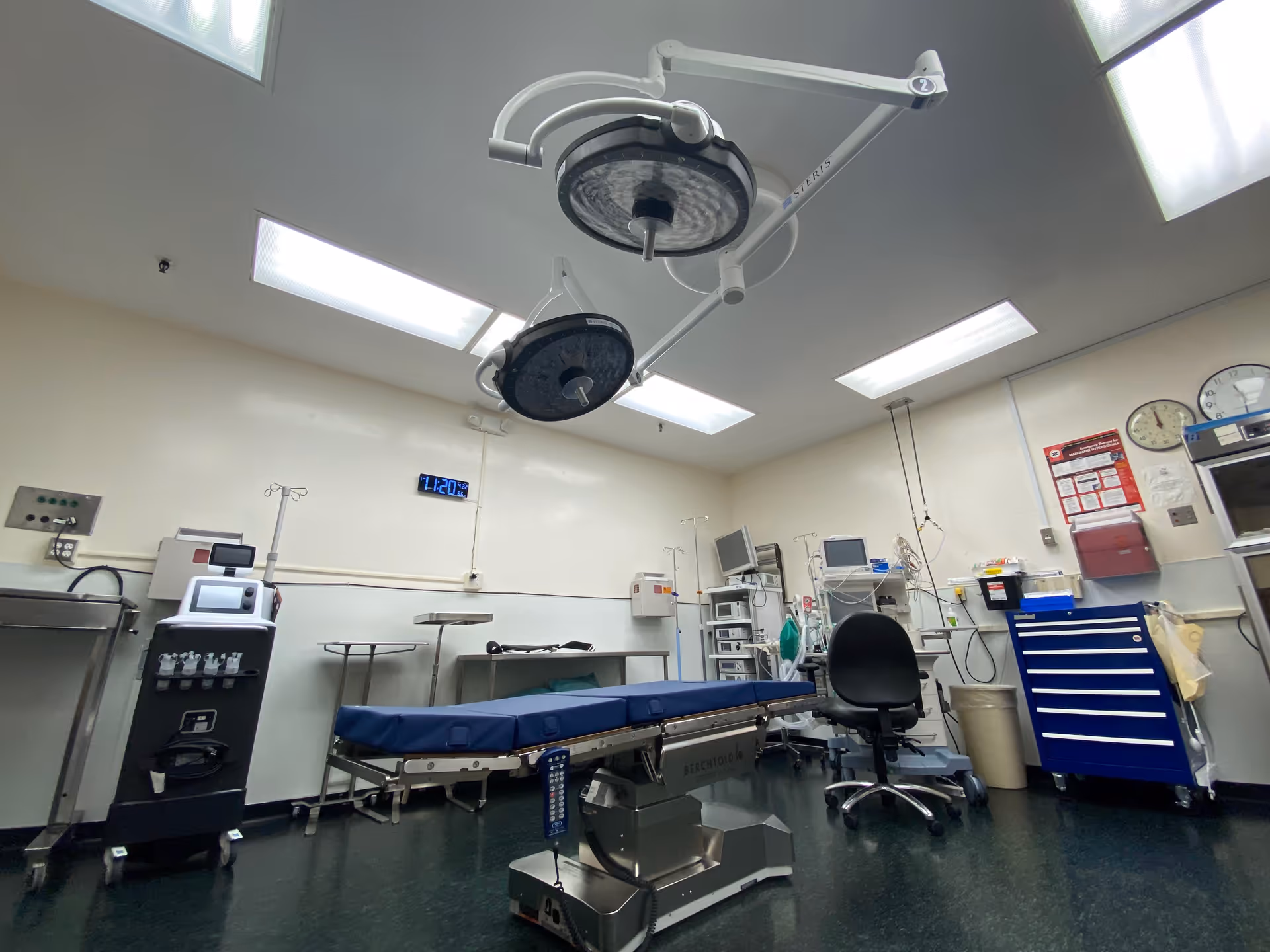 An operating room with overhead surgical lights, an operating table, and medical equipment.